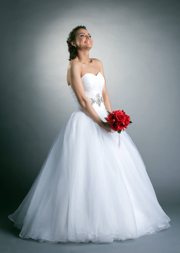 Braut im weißen Brautkleid hält einen Brautstrauß